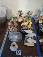 Overview of eight bird-themed music boxes with decorative floral bases and one small white vase
