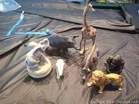Group photo of all animal figurines and piggy bank on black cloth