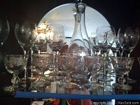 Full set of wine glasses and etched decanter displayed in cabinet with mirror behind