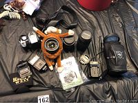 Overview photo showing Canon EOS Rebel camera body, plush monkey toy with lens mounted, three Canon detachable zoom lenses, flashes, lens case, memory cards, user manual, and pouch.