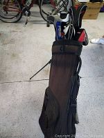 Photo shows black King Cobra golf carry bag upright on stand with several golf clubs visible inside.