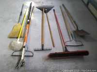 Full layout of various yard and cleaning tools including rakes, brooms, mop, shovel, and pruner