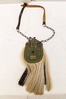 Full view of Scottish sporran bag showing leather flap, metal frame, chain, leather strap, and horsehair tassels.