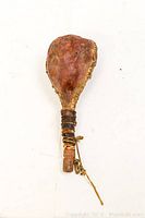 Full view of antique indigenous leather rattle showing pouch and handle wrapped with leather and decorated with beads.
