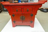 Front view showing two drawers above double-door cabinet, scalloped side brackets,and brass circular lock plate hardware.