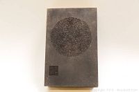 Dark grey brocade-bound album cover featuring circular carved dragon medallion and small square seal carving