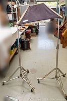 Pair of metal light stands on casters with one soft box mounted on one stand