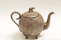 Front right angle view of teapot showing body, handle, spout and feet