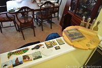 Nine decorative wall tiles with nautical and animal motifs, colorful fish, birds, sailboats and more, placed on a ledge next to a wooden lazy Susan and stainless kitchen tool set.