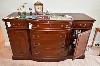 Front view of cherry-finish wooden buffet with drawers and doors, small items on top