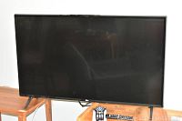 LG TV on wooden stands with remotes visible in front.