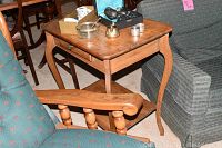 Full view of handmade wooden end table with curved legs, shelf below, minor surface wear visible