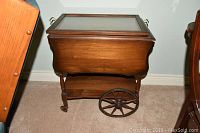 Full view of the wooden wheeled teacart showing removable glass top, folded sides and lower shelf.