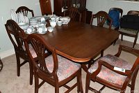 Full view of the wooden dining table with six matching chairs around it, showing table surface and chair seat fabric.