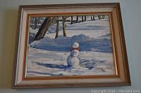 Framed oil painting showing snowman in a snowy wooded landscape under daylight.
