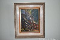 Framed oil painting featuring a forest scene with trees and rocks, signed by Margaret C. Frizzell.