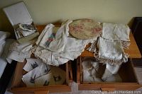 Wide view of assorted linens, napkins, and tablecloths arranged on and in wooden drawers.