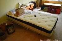Adjustable electric bed with tufted mattress in room setting with items on mattress surface.