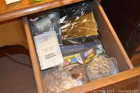 Drawer containing smaller sewing notions, pincushion, and a notepad
