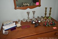 Full view of various candle sticks and decorative items on a wooden dresser beneath a wall mirror.