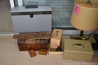 Photo showing full lot from front: gray lockbox, carved cottonwood bark on top of large wooden box with smaller wooden boxes nearby, beige accordion file to right, and a lamp partially visible