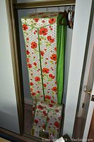 Open dress bag with floral pattern hanging from closet rod, showing full front view