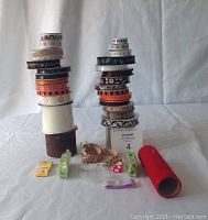Image shows two stacks of multiple rolls of ribbon in mainly orange, black and white colors, arranged on a white fabric background. Some ribbons show Halloween themed prints and various patterns.