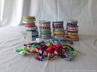 Photo showing 41 rolls of grosgrain ribbon stacked in three columns, and a pile of assorted korker ribbons in front.