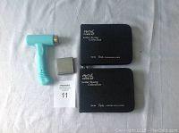 Top-down view of all kit components on white surface: light blue ImpressArt hammer, small metal stamping base, two black zippered cases labeled 'Metal Complex Letter Stamp Collection'
