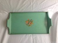 Top view of vintage wooden tray painted green with floral hand-painted center and built-in handles on the sides.