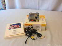 Kodak EasyShare C340 camera on top of original box, instruction manual, and cables shown on table.