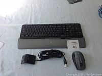 Photo showing Logitech wireless keyboard with wrist rest, Logitech wireless USB mouse with receiver, and a corded USB mouse on a white surface.