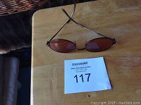 Pair of Serengeti sunglasses on a wooden surface with auction lot tag.