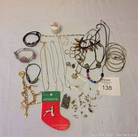 Overview photo showing assorted jewelry and small ceramic trinket box with pink rose lid spread out on white surface
