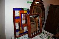 Photo showing stained glass decorative window hanging with colorful geometric pattern and the two wood-framed mirrors.