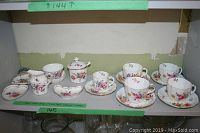 Photo of all pieces laid out on shelf showing cups, saucers, dishes, creamer, and sugar pot.