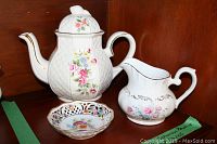 Full view of Arthur Wood teapot, Schumann Bavaria Dresden Line dish, and Ridgway creamer on shelf.