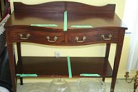 Front view of the wood sideboard showing two drawers with brass handles and a lower shelf.