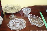 Overview of glass cake stand and assorted glassware laid on wooden surface