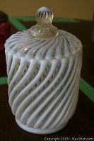 White swirl patterned lidded glass jar with clear knob shown from front