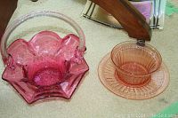 Photo showing cranberry-coloured glass basket and peach-coloured glass bowl with matching plate.
