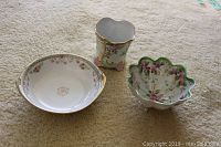 Set of three Nippon hand painted china pieces including two bowls and one vase on beige surface