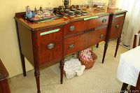 Full front view of the mahogany buffet showing three central drawers and side cabinets with decorative items on top.