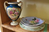 Photo of decorative Nippon style blue vase with floral design, next to two scalloped floral bowls and decorative plate