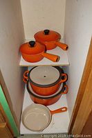 Full view of set on shelving: two saucepans, two round pots, one skillet