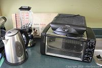 Photo showing all five small kitchen appliances on countertop: electric kettle, blender, food warmer box, toaster oven, and grill on top of the toaster oven.