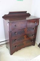 Front view of full dresser showing four large drawers and two small top drawers with round wooden knobs and decorative backboard.