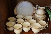 Overall view of the Royal Albert bone china set showing cups, saucers, cake plate, creamer, and sugar bowl with matching gold and brown patterned trim.
