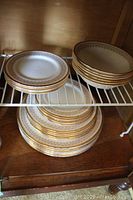 Stack of dinner and salad plates along with bowls showing gold Burlington pattern trim
