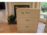 Front view of 3-drawer beige metal filing cabinet in living room area.